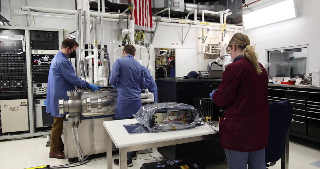 This video shows NASA engineers securing the BurstCube satellite in a thermal vacuum chamber for testing. The first shot shows a thermal vacuum chamber lab at NASA’s Goddard Space Flight Center in Greenbelt, Maryland. The second clip shows Julie Cox (NASA) and Seth Abramczyk (NASA) moving BurstCube, still in a clear protective case, from a table to the chamber platform. The next shot shows Cox and Abramczyk talking over the spacecraft, now without the covering. NASA engineers Franklin Robinson and Elliot Schwartz look on. In the fourth and fifth shots, all four engineers work to move BurstCube into position. In the sixth shot, Cox props one of the solar panels slightly open so they can test it when the spacecraft is in the chamber. In the next shot, Cox, Abramczyk, and Robinson make more adjustments. The eighth shot shows one side of BurstCube, which is engraved with the mission’s logo and the names of partner institutions. The following two clips show wider views of the spacecraft on the chamber platform. The eleventh shot shows Abramczyk and Cox typing at their computers. The twelfth shot shows a computer screen with a feed from a camera on the chamber platform. A smiling Abramczyk pops in and out of view. The thirteenth clip shows Cox deploying one solar panel with Abramczyk and Robinson in the background. The fourteenth shot shows Schwartz, Robinson, Abramczyk, and Colton Cohill (NASA) moving the top of the chamber into place. The fifteenth through nineteenth shots show the engineers steadying the lid as it lowers slowly into place. Shot twenty shows Schwartz securing the top of the lid. Shot twenty-one shows a pan of the sealed chamber. The final shot shows a data readout on a computer screen.

Credit: NASA/Sophia Roberts