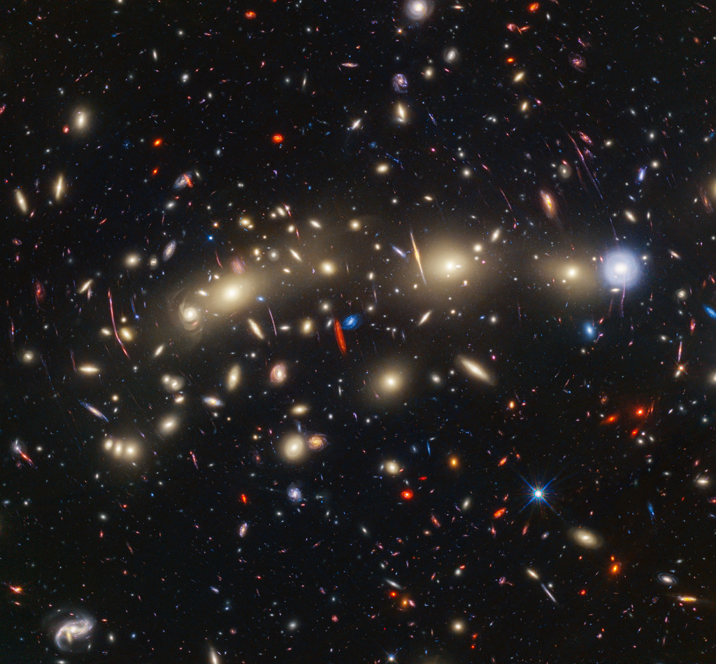 This panchromatic view of galaxy cluster MACS0416 was created by combining infrared observations from NASA’s James Webb Space Telescope with visible-light data from NASA’s Hubble Space Telescope. To make the image, in general the shortest wavelengths of light were color-coded blue, the longest wavelengths red, and intermediate wavelengths green. The resulting wavelength coverage, from 0.4 to 5 microns, reveals a vivid landscape of galaxies that could be described as one of the most colorful views of the universe ever created.MACS0416 is a galaxy cluster located about 4.3 billion light-years from Earth, meaning that light we see now left the cluster shortly after the formation of our solar system. This cluster magnifies the light from more distant background galaxies through gravitational lensing. As a result, the research team has been able to identify magnified supernovae and even very highly magnified individual stars.Those colors give clues to galaxy distances: The bluest galaxies are relatively nearby and often show intense star formation, as best detected by Hubble, while the redder galaxies tend to be more distant, or else contain copious amount of dust, as detected by Webb. The image reveals a wealth of details that are only possible to capture by combining the power of both space telescopes.In this image, blue represents data at wavelengths of 0.435 and 0.606 microns (Hubble filters F435W and F606W); cyan is 0.814, 0.9, and 1.05 microns (Hubble filters F814W, and F105W and Webb filter F090W); green is 1.15, 1.25, 1.4, 1.5, and 1.6 microns (Hubble filters F125W, F140W, and F160W, and Webb filters F115W and F150W); yellow is 2.00 and 2.77 microns (Webb filters F200W, and F277W); orange is 3.56 microns (Webb filter F356W); and red represents data at 4.1 and 4.44 microns (Webb filters F410M and F444W).